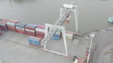 A high angle HD footage a huge ship crane above cargo containers of ships at the port