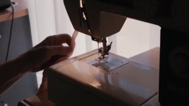 Female worker cutting thread while sewing on machine