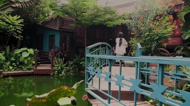 Woman Walking Bridge Leading Quaint Wooden Cottage Pond — Video