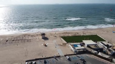 An aerial view of the shiny sea with flying parachutes over the beach