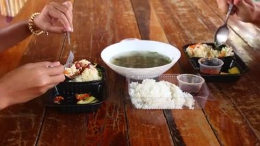 İki kişinin Bai Cha ya da Khmer pilav ve Samlor yerken ya da paket paket servis çorbası içerken çekildiği zaman.