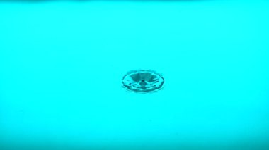 Water droplet hits blue still water at 1000fps