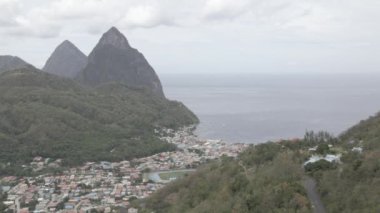 An aerial drone footage of the houses surrounded by cliffs on the beach on St Lucia island
