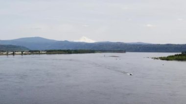 A Drone shot of a speed boat in the Columbia River with a snow capped mountain in the background