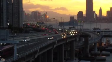 Victoria Limanı, Hong Kong 'da günbatımında arabaların ve modern binaların olduğu bir trafik yolu manzarası.