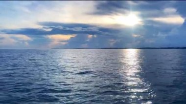 Güneş doğarken dalgalanan güzel bir okyanus suyu görüntüsü.