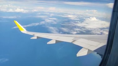 Güzel bir uçak kanadı manzarası okyanusun üzerinde uçuyor ve beyaz kabarık bulutlar