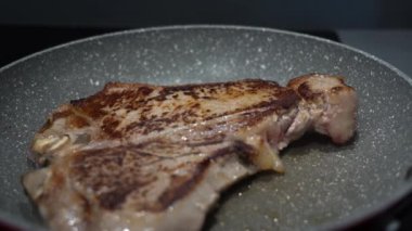 Tavada kızaran T-Bone bifteğinin yakın çekimi.