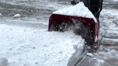 Kışın bir adam, kar temizleme ekipmanıyla yolu temizler.