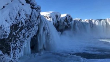 Buzlu şelale İzlanda 'da aydınlık bir günde, nehirde kar ve buz parçaları akıyor.