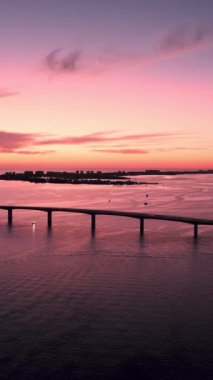 An aerial view of sea bridge in a clear blue sea at purple sunset