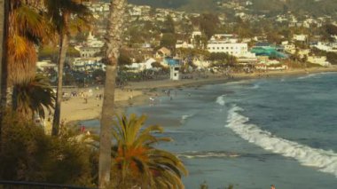 A beautiful landscape of a beach and buildings from palm trees
