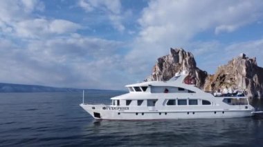 A white ship moving with a cliff at the back on Lake Baikal's best location in Irkutsk, Russia