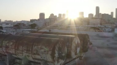 An aerial view of the rusty containers on a roof of a building in a modern city