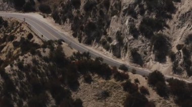 Tepelerle çevrili asfalt yolda haykırışların manzaralı bir görüntüsü.
