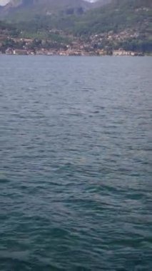 A vertical shot of a coastline captured from the boat on the background of forested hills
