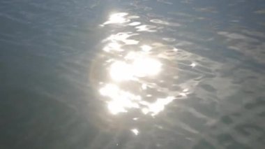 The warm sun reflecting off soft waves rippling in the ocean on a bright sunny day