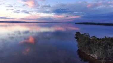 A scenic view of a pink sunset reflected in the lake