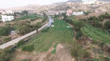 Mesmerizing drone view of a beautiful mountainous valley, field, channel and city in northern Saudi Arabia under cloudy sky