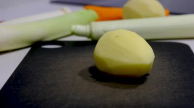 A closeup of the footage of the hand cutting the potato with a knife surrounded by other vegetables.