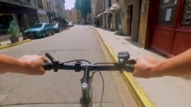 A closeup of a person cycling through the old town in Cremieu, France on a hot summer day