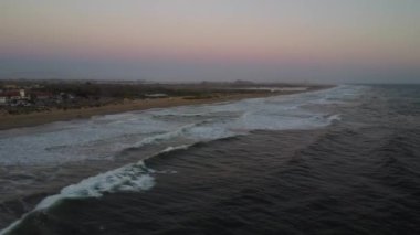 A mesmerizing view of the beach during sunset beautiful waves under a pastel sky