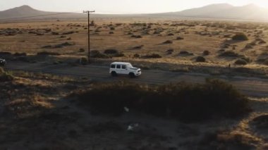 Beyaz bir Mercedes G Wagon çölde sürüyor.