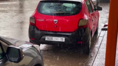 Red taxi parked on the road side during a stormy day outdoors