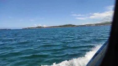 A beautiful wake water splash from a ferry boat in the ocean and greenery hills in the background
