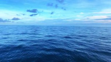 A scenic view of the seascape against cloudy dusk sky at sunset as seen from a moving boat