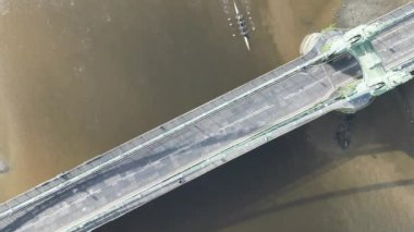 An aerial top view of rowers passing under Hammersmith Bridge in London, UK