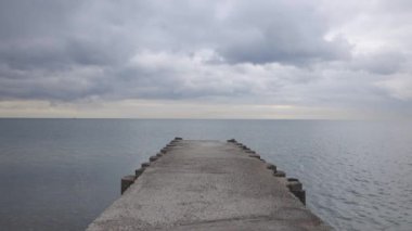 A view of gentle waves passing along cement dock on sea