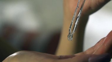 Hand of woman with pipette dripping drops of a serum on the hand