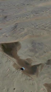 An aerial view of a car driving on the sandy Birubi Beach in Anna Bay, Australia