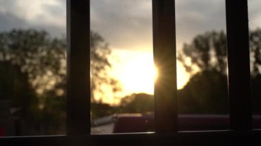 A beautiful distant view of sunset light flares through a fence