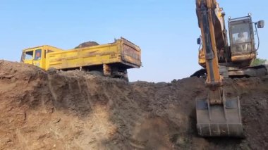 Earthmoving equipment. Yellow excavator digging the ground. The Excavator bucket scoops up the soil on a constructionist in India.