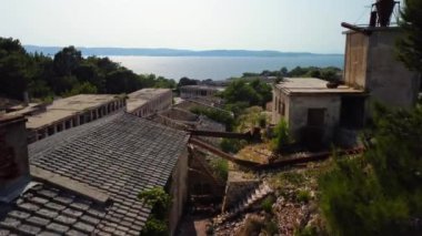 A drone footage of an abandoned prison building with a lake in the background in Croatia