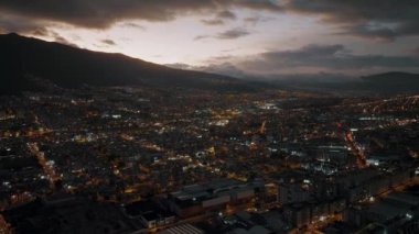 An aerial footage of the city of Quito in Ecuador at night in cloudy sky background