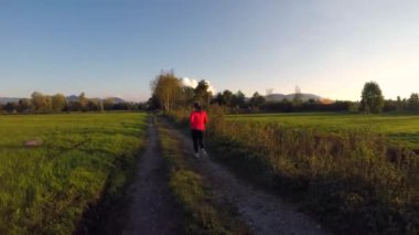 Sabahları yeşil bir arazide koşan beyaz bir kadının görüntüsü.