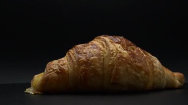 Koyu arkaplanda yeni pişmiş bir kruvasan.