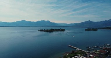 A drone shot over the small touristic town Gstadt am Chiemsee in Bavaria by the sea with mountains