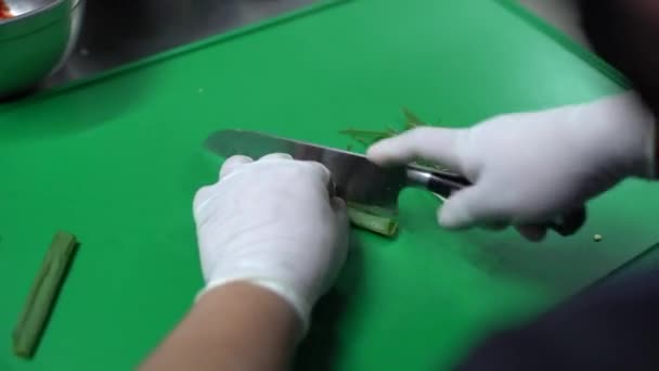 緑のボード上の緑のタマネギを切断白い手袋で男の手のクローズアップショット — ストック動画