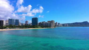 Kahanamoku plajının panoramik manzarası ve güneşli bir günde Waikiki, Hawaii 'de bulutlu bir gökyüzünün altında modern binalar.