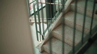 Merdivenlerden inen, kot pantolonlu ve köşeden dönen bir kadın.