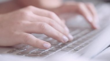 A closeup of the woman's hands typing on the keyboard.