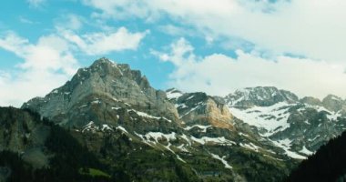 A time lapse of clouds over snow covered mountains in