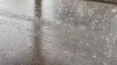 Heavy raindrops fall on the asphalt road