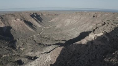 An aerial view of couple standing on a rocky cliff overlooking the valley