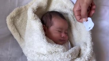 Beyaz bir çarşafın üzerinde uzanmış tatlı, huzurlu bebek. İçeride gündüz uykusunun tadını çıkar.