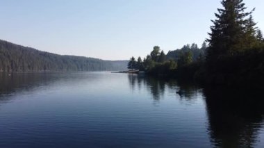 Etrafı yeşil ağaçlarla çevrili sessiz bir göl.